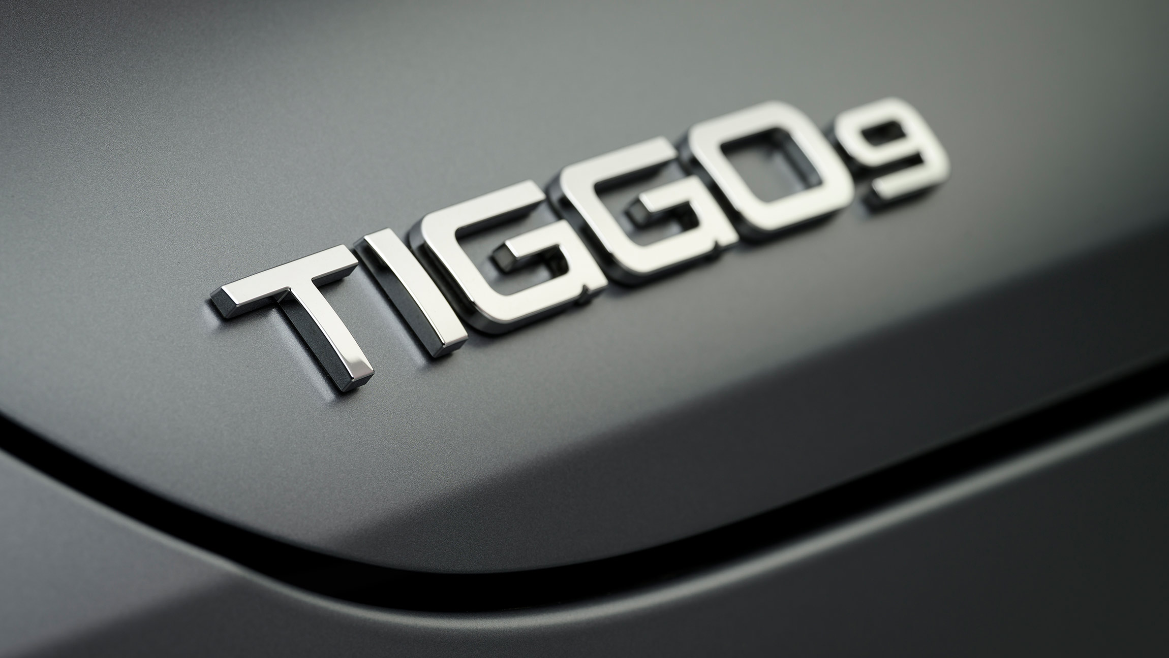 Close-up of Chery Tiggo 9 chrome badge on a matte grey rear panel