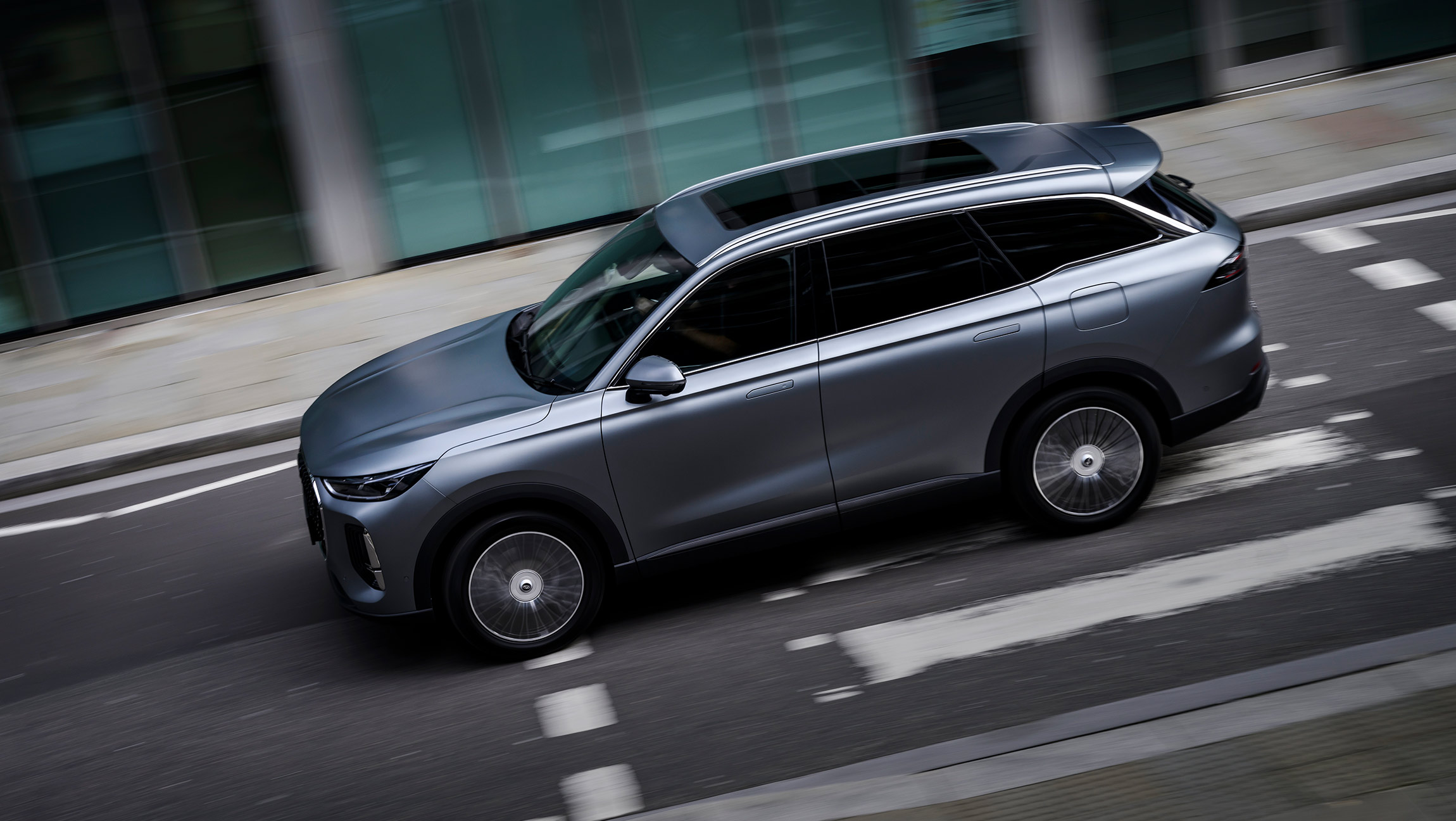 Chery Tiggo 9 CSH SUV side profile in matte grey finish, driving on an urban street